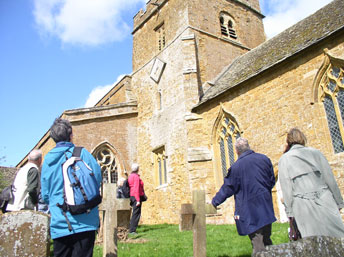 Members of the group taking a walk round the church of St. Peter, Hanwell in north Oxfordshire on a breezy April day this year.